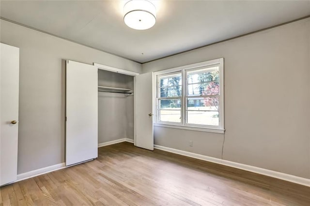 unfurnished bedroom featuring a closet, wood finished floors, and baseboards