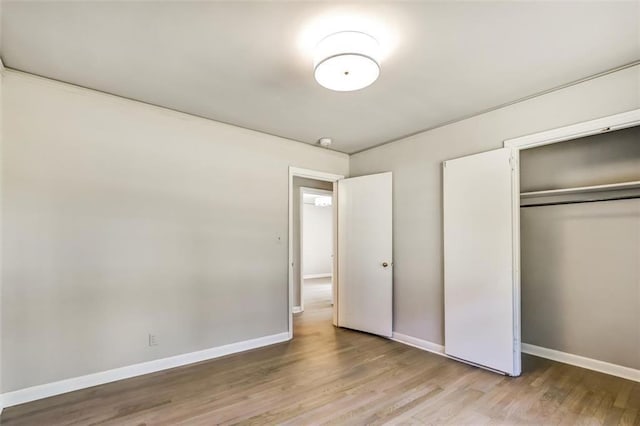 unfurnished bedroom with a closet, wood finished floors, and baseboards