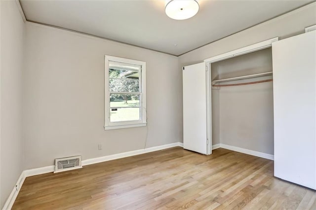 unfurnished bedroom featuring visible vents, freestanding refrigerator, baseboards, a closet, and light wood-type flooring
