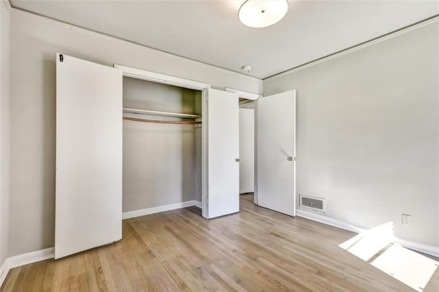 unfurnished bedroom featuring baseboards, visible vents, wood finished floors, and a closet