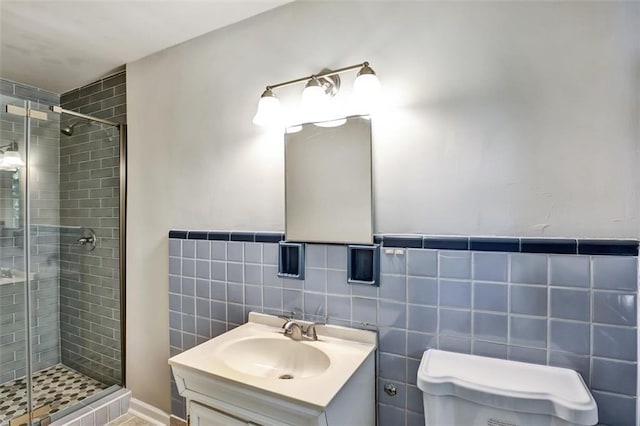 bathroom featuring toilet, vanity, a shower stall, and tile walls