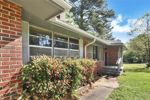 view of side of property featuring brick siding and a yard