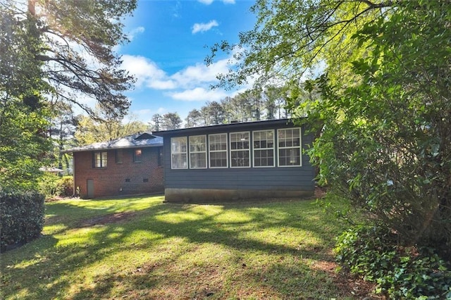 view of home's exterior with a sunroom, a yard, and brick siding