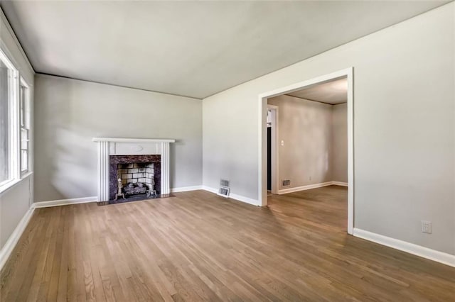 unfurnished living room with a high end fireplace, wood finished floors, and baseboards