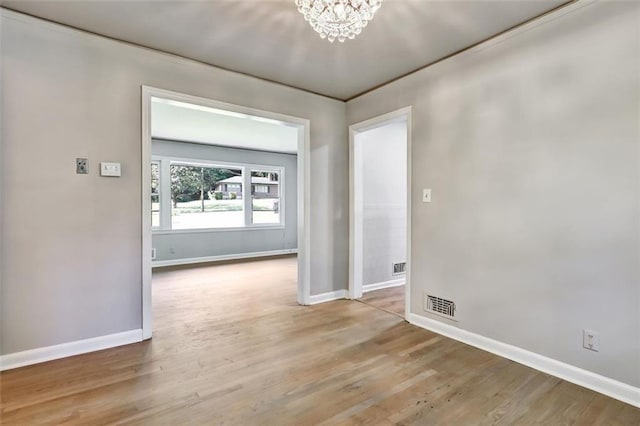 empty room with visible vents, light wood-style flooring, a chandelier, and baseboards