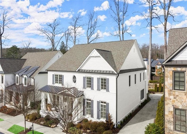 modern inspired farmhouse with metal roof, a shingled roof, stone siding, stucco siding, and a standing seam roof