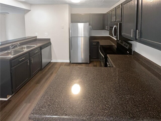 kitchen featuring appliances with stainless steel finishes, kitchen peninsula, sink, and dark hardwood / wood-style floors