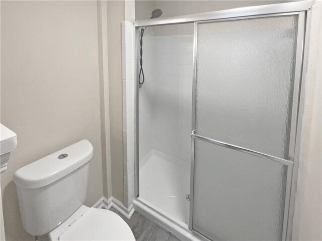 bathroom featuring an enclosed shower, wood-type flooring, and toilet