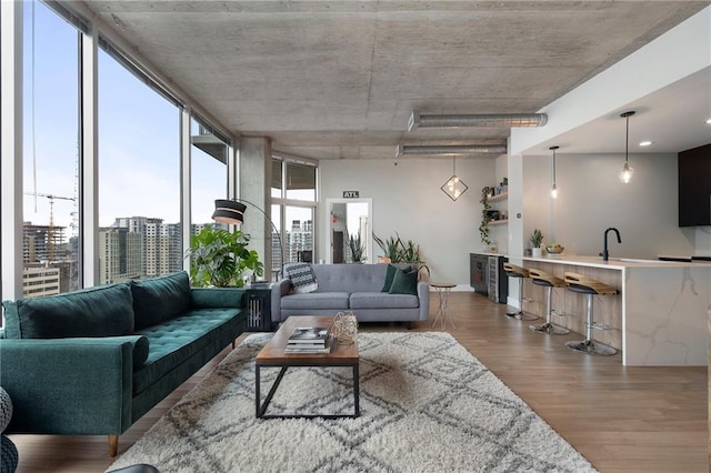 living room with floor to ceiling windows, plenty of natural light, light hardwood / wood-style floors, and sink