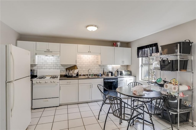 kitchen featuring tasteful backsplash, white appliances, light tile floors, sink, and white cabinetry