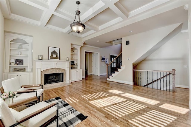 living room with coffered ceiling, a premium fireplace, built in features, and beam ceiling