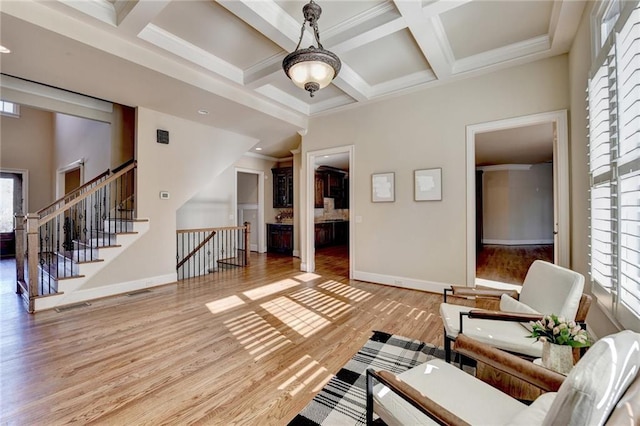 living room with beam ceiling, light hardwood / wood-style flooring, coffered ceiling, and crown molding