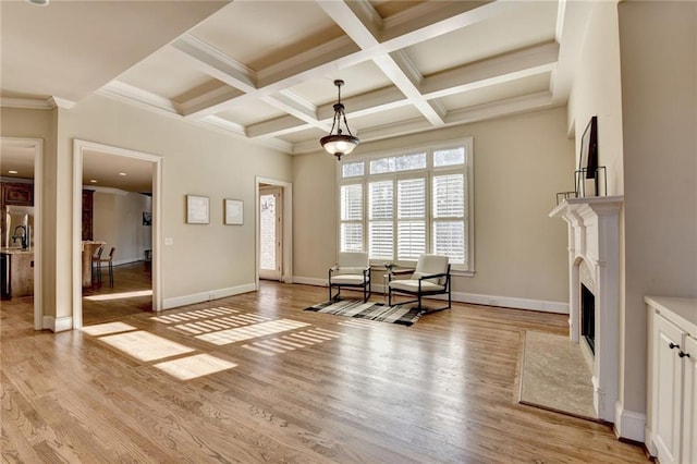 living area featuring coffered ceiling, light wood-type flooring, ornamental molding, a fireplace, and beam ceiling