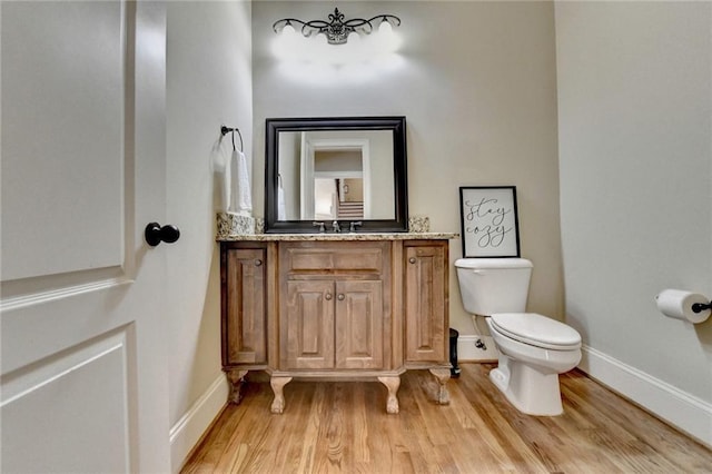 bathroom with toilet, hardwood / wood-style floors, and vanity