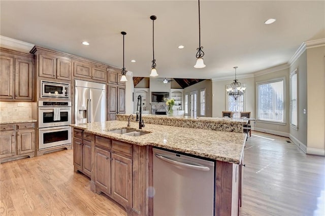 kitchen with sink, built in appliances, hanging light fixtures, a chandelier, and a kitchen island with sink