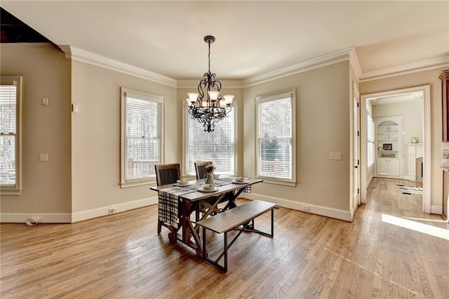 dining space with a notable chandelier, light wood-type flooring, and crown molding