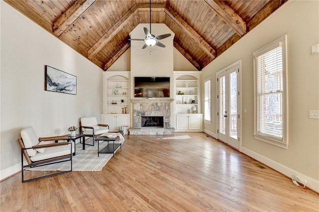 living room featuring high vaulted ceiling, light hardwood / wood-style floors, wood ceiling, and a stone fireplace