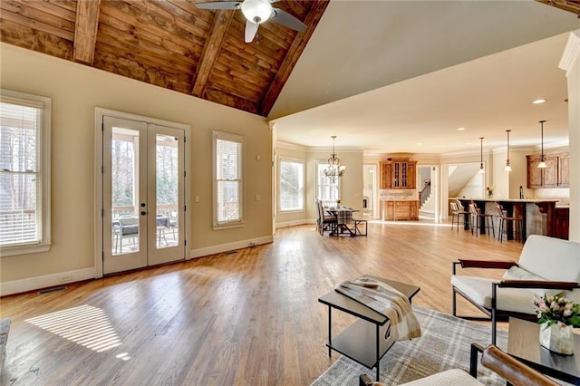 living room with vaulted ceiling with beams, french doors, light wood-type flooring, ceiling fan with notable chandelier, and wood ceiling