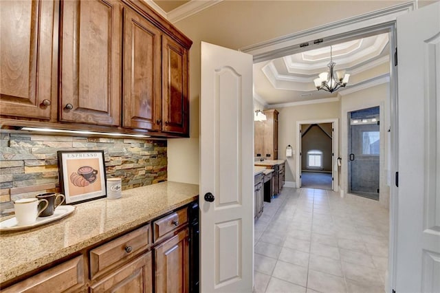 kitchen featuring a chandelier, crown molding, light stone countertops, pendant lighting, and light tile patterned flooring