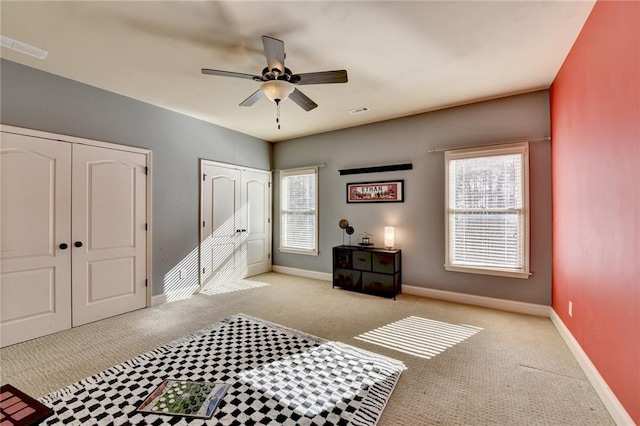 carpeted bedroom with multiple windows and ceiling fan