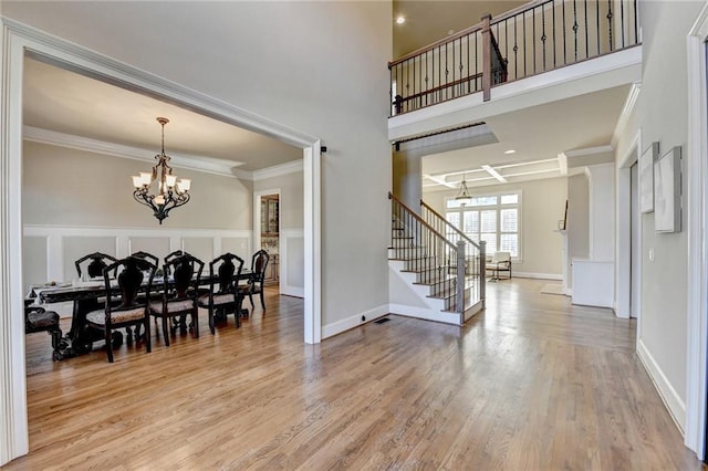 dining space with an inviting chandelier, ornamental molding, and wood-type flooring