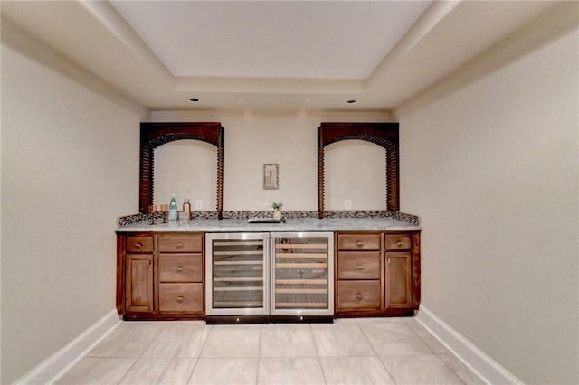 bar featuring beverage cooler, a raised ceiling, and light tile patterned flooring