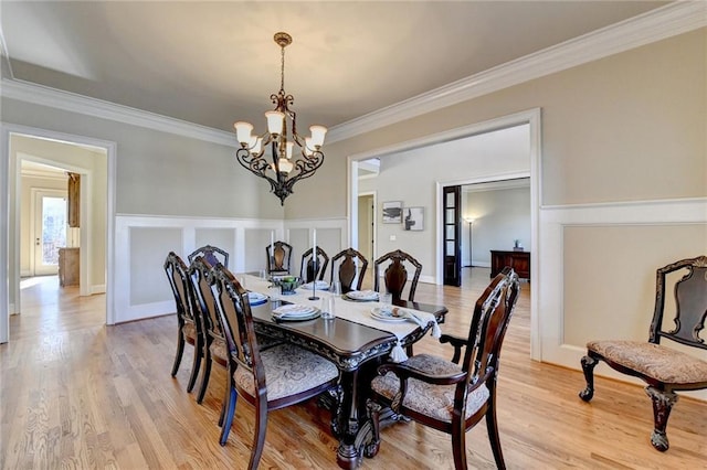 dining room featuring crown molding, light wood-type flooring, and a notable chandelier