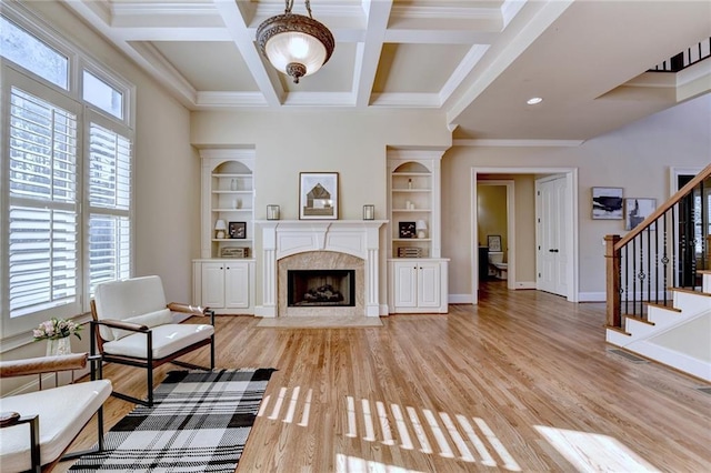 living room with a premium fireplace, coffered ceiling, built in features, and plenty of natural light