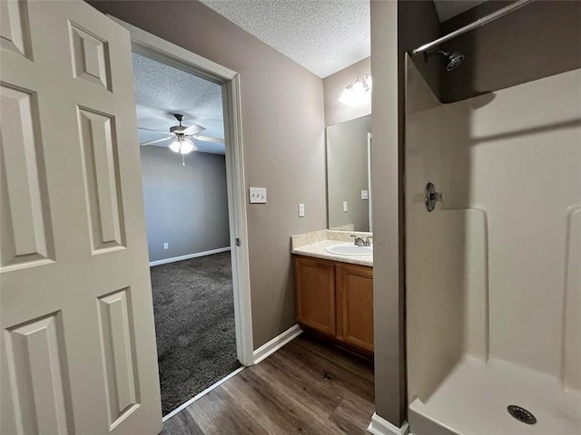 bathroom featuring vanity, ceiling fan, a shower, and a textured ceiling