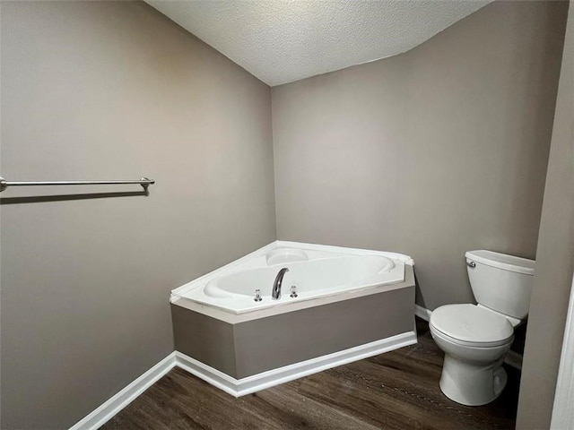 bathroom with a bath, hardwood / wood-style floors, a textured ceiling, and toilet