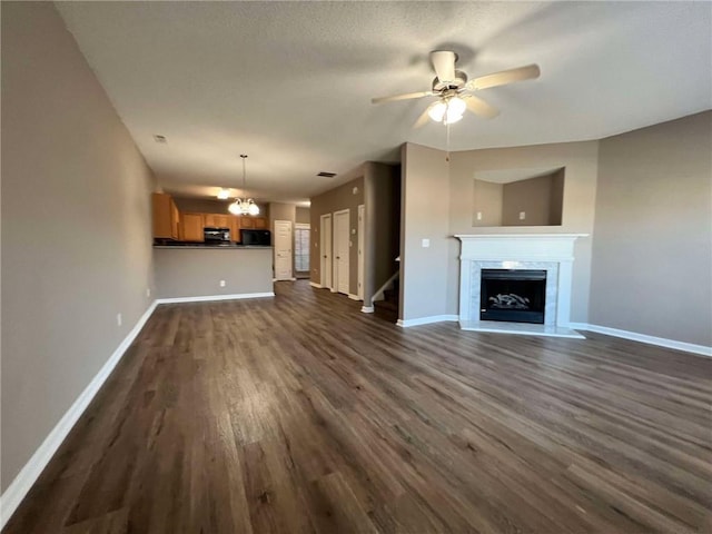 unfurnished living room with dark wood-type flooring and ceiling fan with notable chandelier