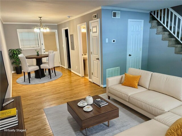 living room with crown molding, light hardwood / wood-style flooring, and a notable chandelier