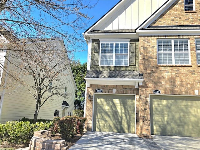 view of front of property featuring an attached garage, driveway, board and batten siding, and brick siding