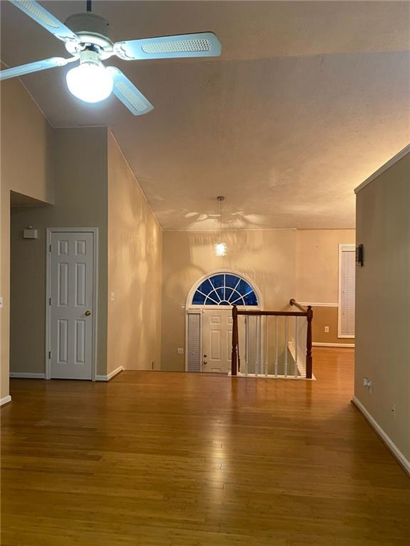 unfurnished room with ceiling fan, high vaulted ceiling, and wood-type flooring