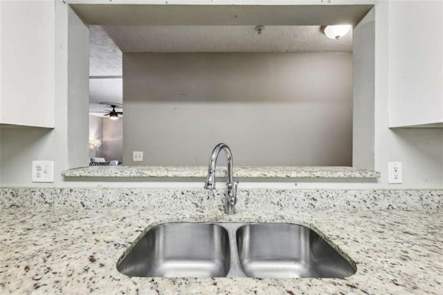 details featuring light stone counters, sink, and ceiling fan