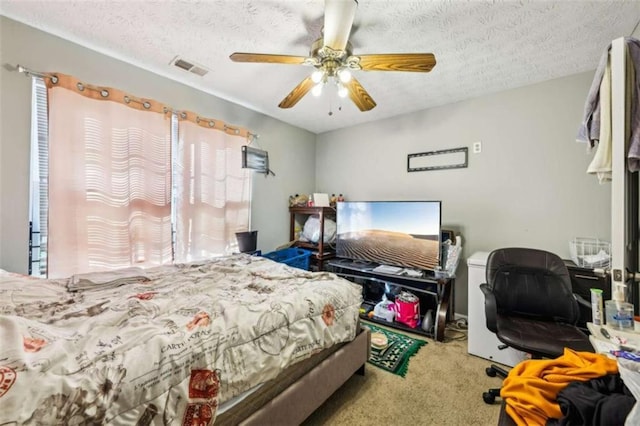 carpeted bedroom with ceiling fan and a textured ceiling