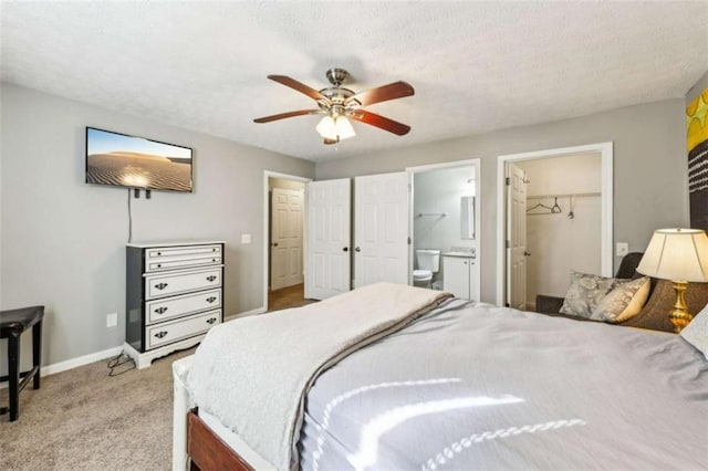 bedroom with ceiling fan, a spacious closet, a textured ceiling, light colored carpet, and a closet