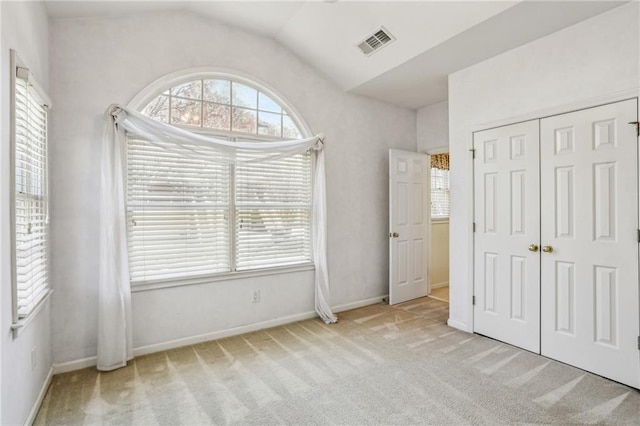 unfurnished bedroom with visible vents, lofted ceiling, a closet, carpet floors, and baseboards