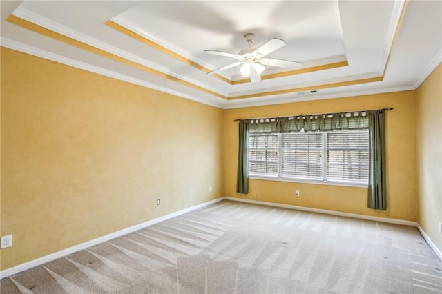 spare room with a raised ceiling, carpet flooring, baseboards, and ornamental molding