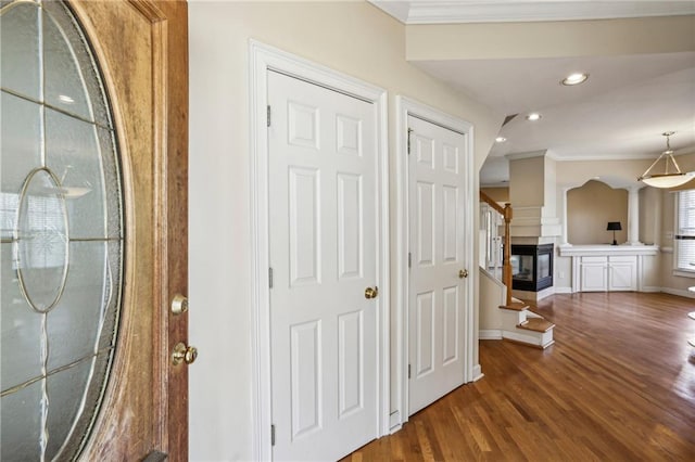 hallway with wood finished floors, baseboards, recessed lighting, stairs, and crown molding