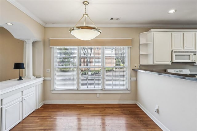 unfurnished dining area featuring visible vents, arched walkways, crown molding, baseboards, and ornate columns