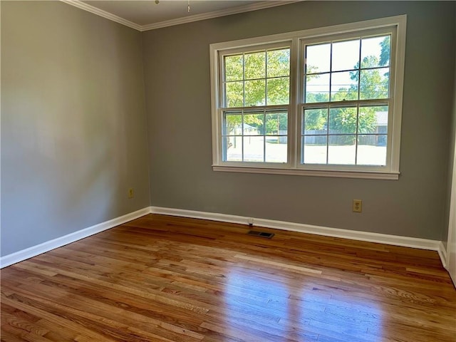 unfurnished room with baseboards, ornamental molding, wood finished floors, and a healthy amount of sunlight