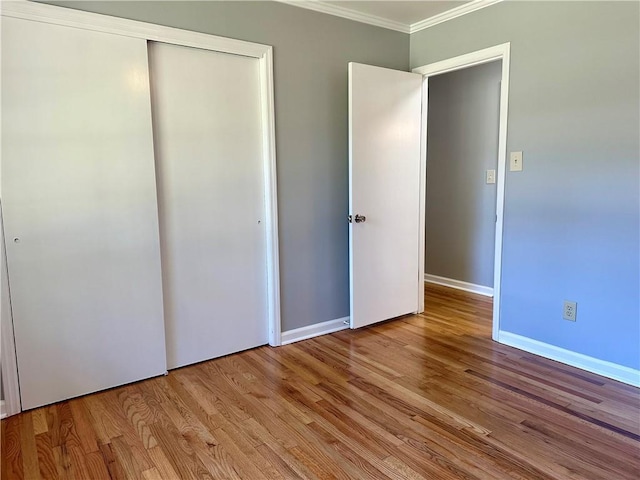 unfurnished bedroom with crown molding, baseboards, a closet, and wood finished floors