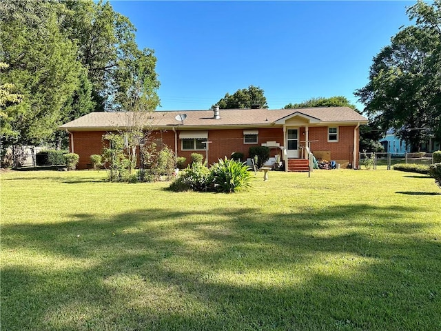 back of house with fence, a lawn, and brick siding