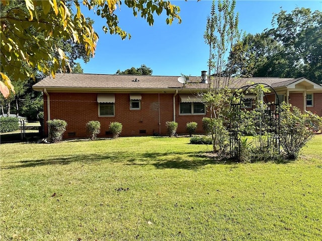 rear view of property with a yard, crawl space, and brick siding