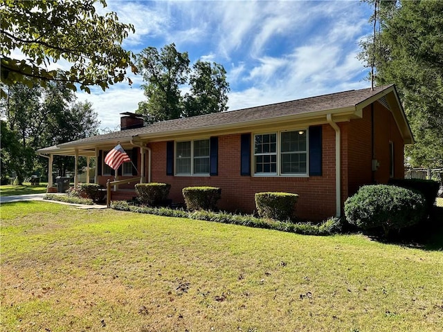 ranch-style home with brick siding, a chimney, covered porch, and a front yard