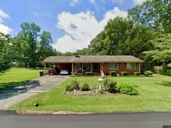 ranch-style home featuring driveway, a chimney, a carport, and a front lawn