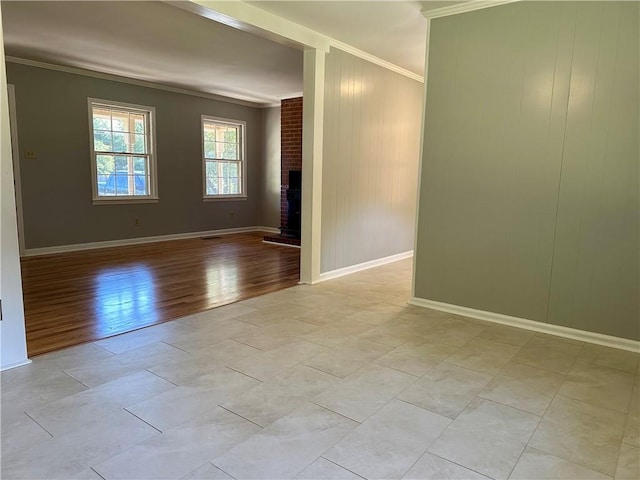unfurnished room featuring crown molding, baseboards, a brick fireplace, and light wood finished floors