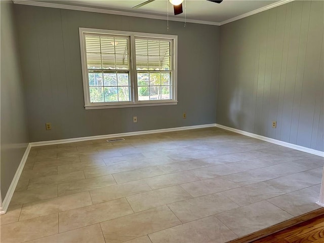 spare room featuring a ceiling fan, baseboards, wood walls, and ornamental molding