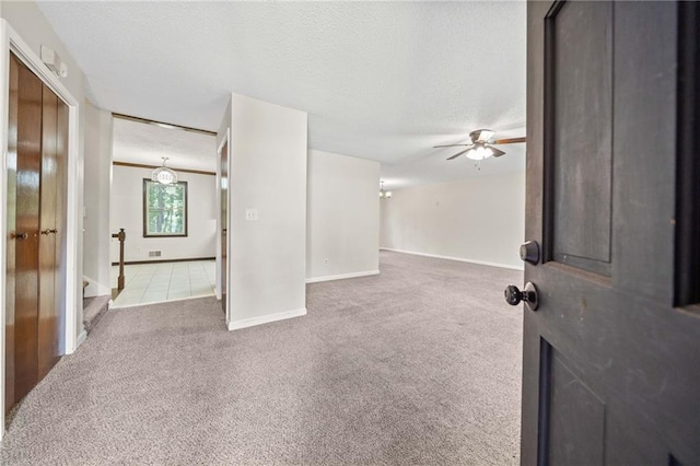 empty room featuring ceiling fan, a textured ceiling, and carpet flooring